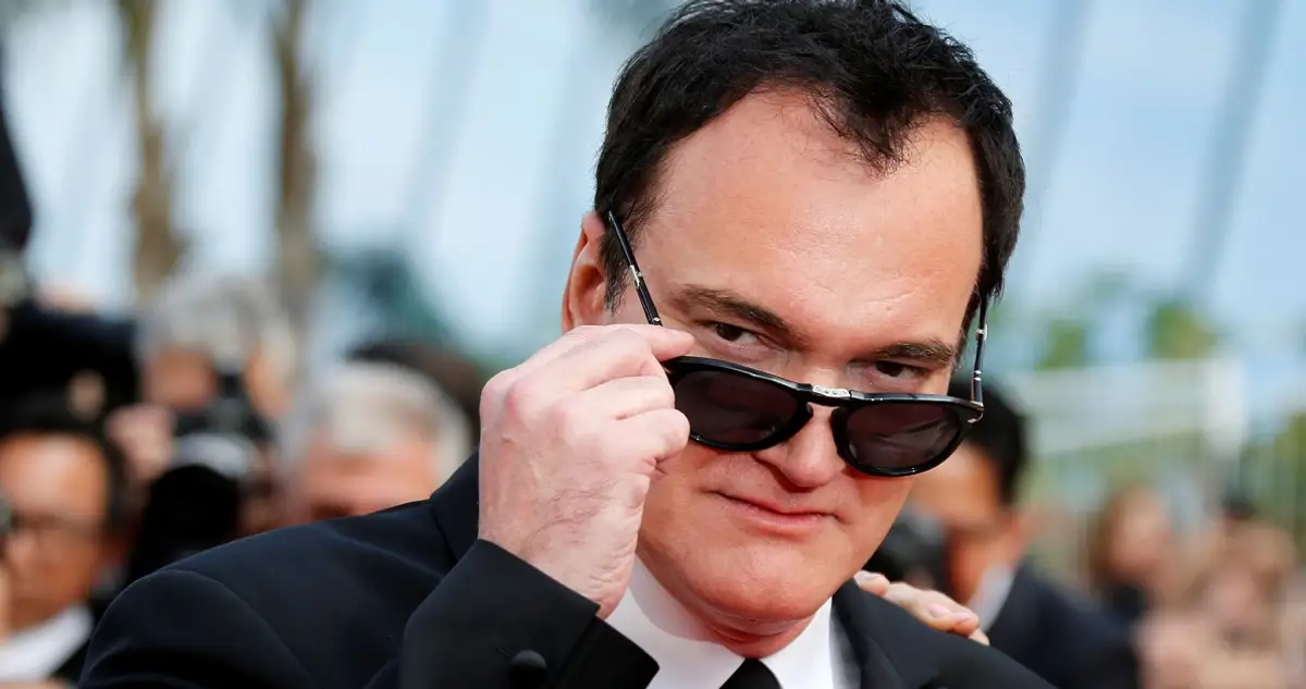 Diretor Quentin Tarantino sorrindo, segurando uma figura de anime